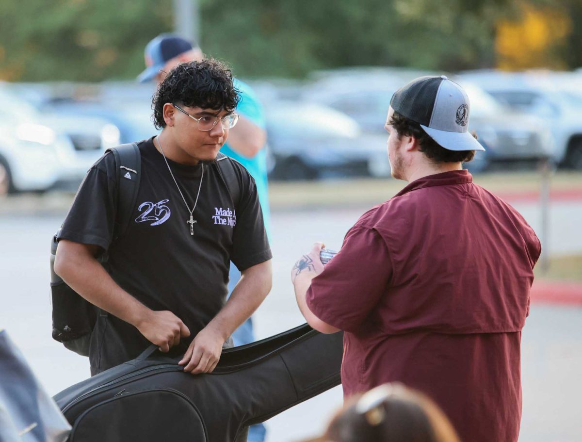 AFTER SHOW. Sophomore Anthony Landeros talks to another student as he zips up his guitar case after Noche de Ritmo comes to an end on Oct. 14, 2025.