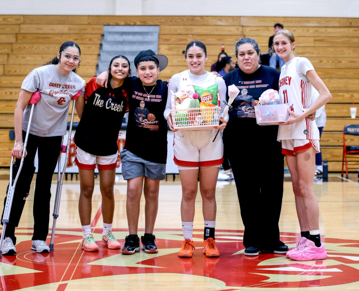 Senior Yeiry Zamudio stands with her family and teammates on the court holding a gift basket from her family in celebration of senior night on Feb. 7. 